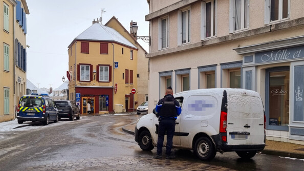 Un gendarme de dos contrôle un fourgon blanc sur l'axe d'une commune