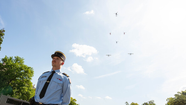 Vue en contre-plongée d'un gendarme mobile et dans le ciel les hélicoptères