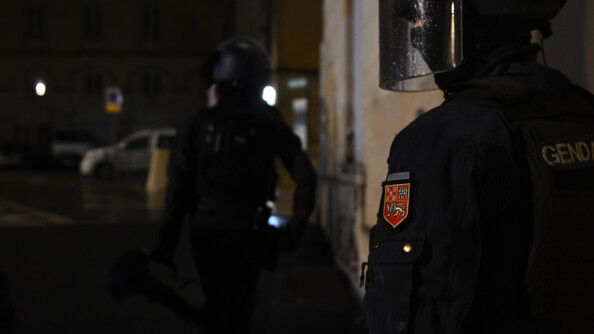 Deux gendarmes casqués de nuit l'un derrière l'autre dans les rues.