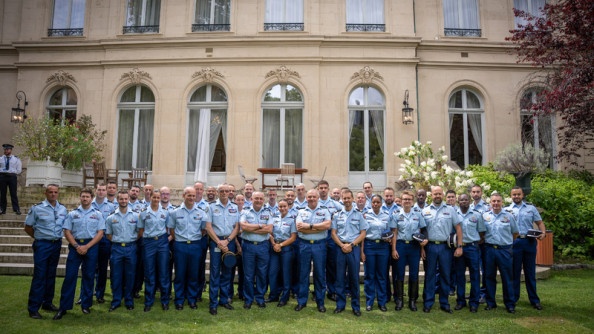Photo de groupe, rassemblant des gendarmes, posant debout sur la pelouse devant la façade de l'hôtel de Beauvau
