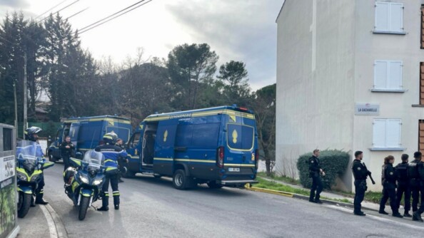 De jour et en extérieur, des gendarmes mobiles se rendent dans un quartier. Deux Iris Bus ainsi que deux motos de la gendarmerie sont également sur l'image.