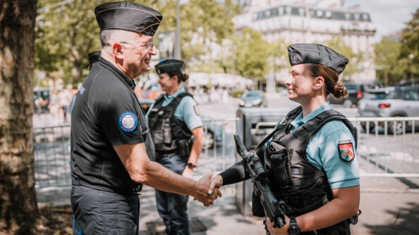Le directeur général de la gendarmerie nationale serre la main d'une femme gendarme, dans les rues de Paris
