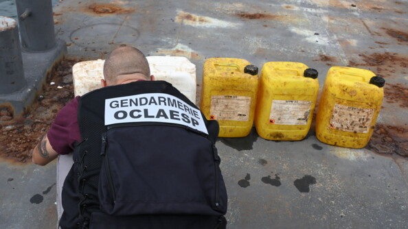 Un gendarme de l'OCLAESP examine des bidons sortis de l'eau, source de pollution.
