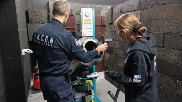 La para-sportive Gaëlle Edon, Sportive de haut-niveau de la Défense - Gendarmerie (SHND-G), à gauche, de dos, avec à sa gauche un expert du département ballistique de l'Institut de recherche criminelle de la gendarmerie nationale.