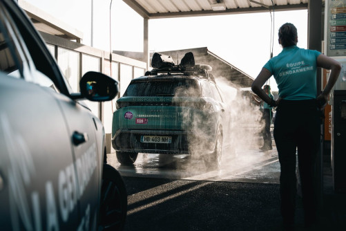 Gendarme nettoyant un véhicule de la caravane après course.