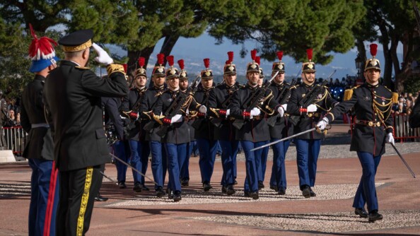 Un détachement de fantassins de la garde républicaine passent au pas devant deux autorités. L'officier devant ses troupes salue au sabre