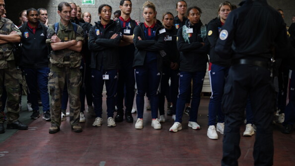 Face à un gendarme du GIGN, de dos et à droite de l'image, une quinzaine de sportifs de la Défense alignés. A gauche, deux militaires en treillis les accompagnent