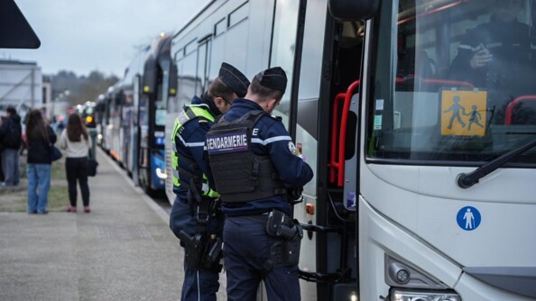 De jour, deux gendarmes en tenue, controlent un bus scolaire
