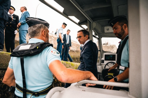 Le ministre de l'Intérieur, Bruno Retailleau, se tient debout sur une embarcation, aux côtés de gendarmes