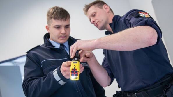 Un policier allemand tient un taser français en main et écoute la présentation d'un gendarme du PSIG sur l'utilisation du moyen de défense