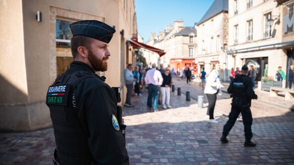 Un gendarme en premier plan avec derrière, en flou les rues de Bayeux et la foule de visiteurs venus assiter aux cérémonies.