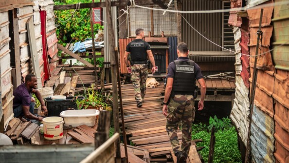 Gendarmes de la compagnie de Matoury de dos dans un quartier informel.