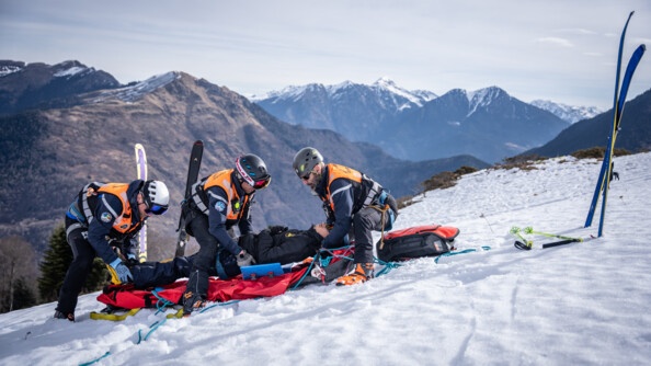 Trois gendarmes installent dans un brancard une victime. Il fait jour.