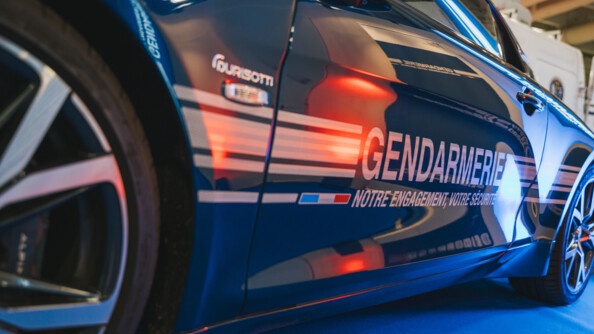 Photo en gros plan de la portière d'une Alpine de la gendarmerie de couleur bleue, portant une sérigraphie de la gendarmerie avec la mention "Notre engagement, votre sécurité". Photo prise lors du salon de l'Auto 2024, à Paris.