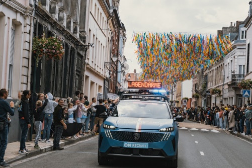 Véhicule de la caravane gendarmerie avançant dans une rue décorée.