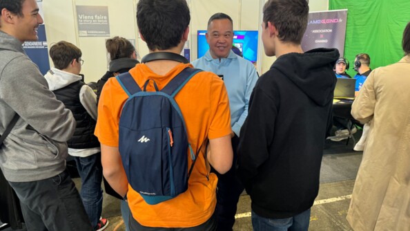 Ubn gendarme échange avec trois visiteurs de la Gamer's Assembly, de dos.