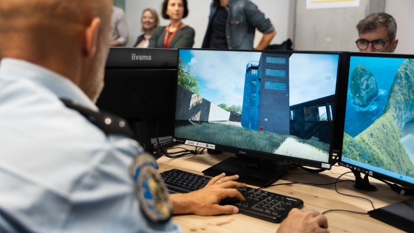 Photo de dos d'un g&eacute;n&eacute;ral de gendarmerie en train de d&eacute;couvrir la plateforme cr&eacute;&eacute;e par les &eacute;l&egrave;ves de Ynov-Campus. Sur l'&eacute;cran, on voit une tour.