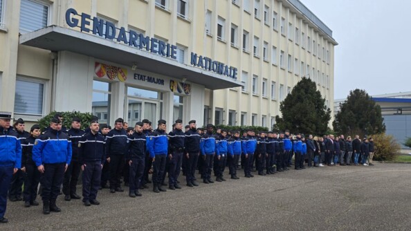 Des gendarmes au garde &agrave; vous devant une caserne sur laquelle est &eacute;crite "Gendarmerie nationale".