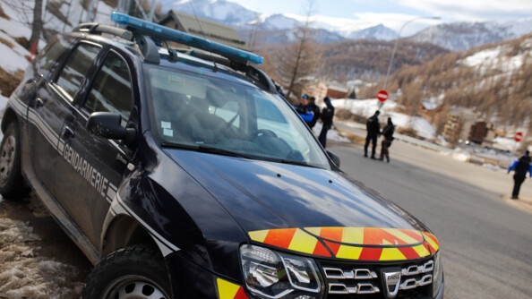 Vue sur un Duster sérigraphié de la gendarmerie , derrière e flou, quelques gendarmes et les montagnes