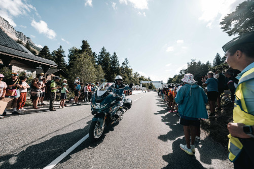 Un motocycliste de la gendarmerie sur la route salue le public.