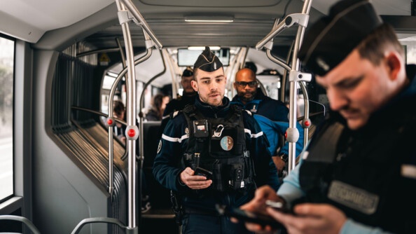 Deux gendarmes français, accompagnés d'un policier suisse, effectuent un contrôle des passagers dans un autobus.