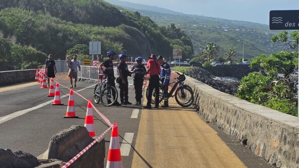Des gendarmes &agrave; v&eacute;lo &eacute;changent avec des habitants sur un pont, sur lequel des plots sont align&eacute;s, et un ruban a &eacute;t&eacute; install&eacute;, apr&egrave;s le passage du cyclone Garance sur l'&icirc;le de la R&eacute;union.