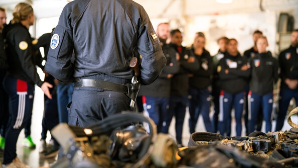 Un homme du GIGN de dos, face à lui, flous, les sportifs de haut niveau