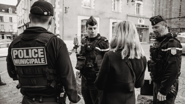 2 gendarmes et un policier discutant avec une femme de dos.