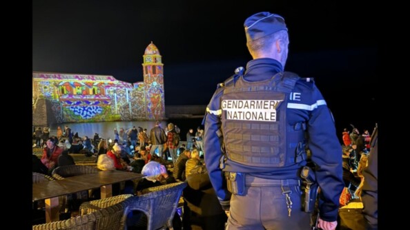 Le soir du nouvel an, un gendarme de dos, de nuit, surveille une zone très fréquentée de la ville.