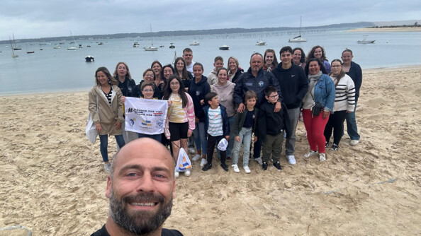 Sur la plage, 25 personnes, femmes et enfants, réunis autour de la banière des képis psecalunes