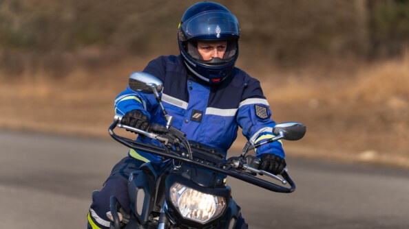 un motard de la gendarmerie tenant le guidon de sa moto et regardant au loin