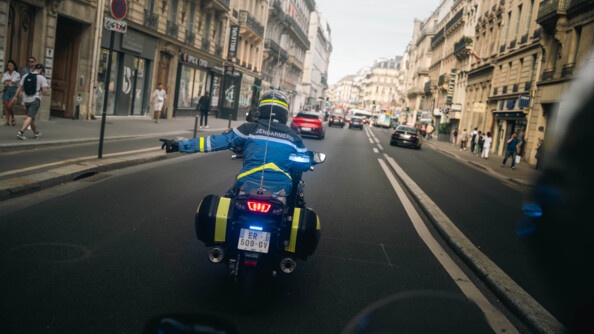 Mootcycliste faisant un geste de la main au centre de Paris.
