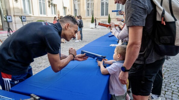 Un enfant s'essaye au tir avec le pentathlète Christopher Patte, sportif de haut niveau de la Défense - gendarmerie.