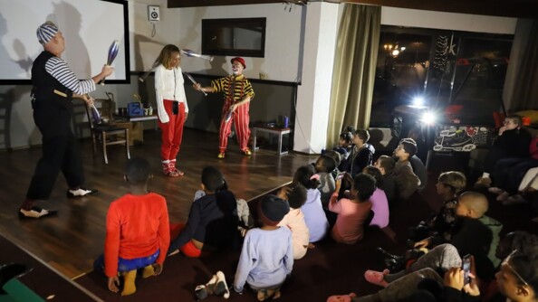 Des enfants rigolent devant des clowns qui font un numéro