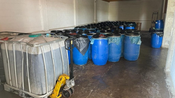 Plusieurs fûts d'huile de friture usagée entreposés dans un hangar.
