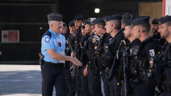 Un général 5 étoiles de la de gendarmerie s'apprête à serrer la main d'un gendarme qui  est aligné avec une quinzaine d'autres gendarmes mobiles en noir