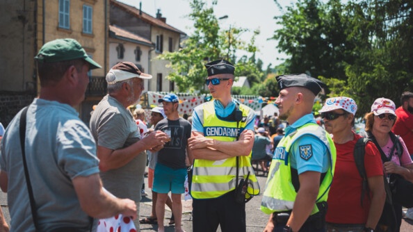 Deux gendarmes échangent avec les gens venus nombreux assister aux passages de la caravane et des courreurs.