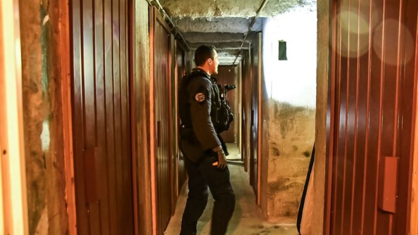 Fouille de cave par un gendarme équipé d'une lampe torche.