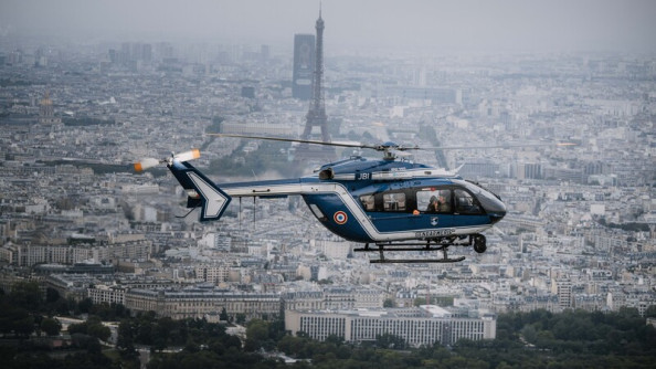 La photo représente un hélicoptère bleu de la gendarmerie survolant Paris