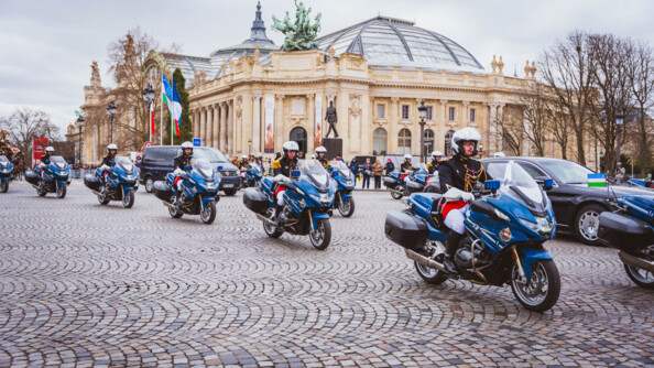 Devant le grad palais passent les motards de la Garde républicaine, escortant une berline noire arborant le drapeau de l'Ouzbékistan et un van noir