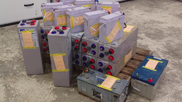 Plusieurs batteries électriques empilées sur une palette en bois.