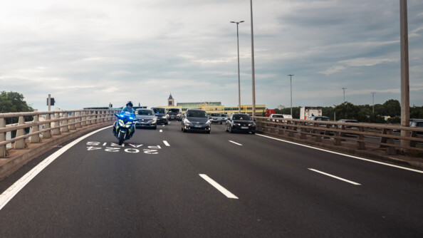 Motocycliste escortant des véhicules sur la voie réservée JOP.