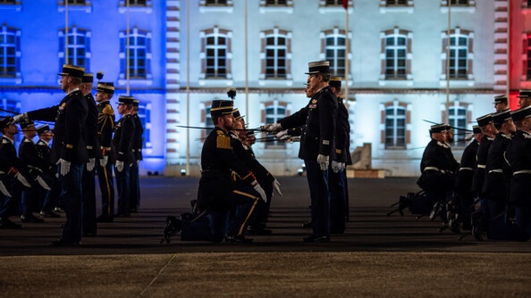 Les officiers issus du rang alignés et à genoux devant leurs parrains qui les adoubent