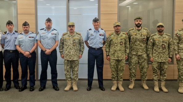Dix officiers de la gendarmerie française et de la Kuwait National Guard, côte à côte, revêtus de leurs tenues respectives, pantalons bleus et chemisettes bleues pour les premiers et treillis pour les seconds.