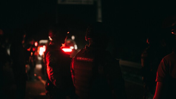 Gendarmes de dos et casqués dans la nuit.