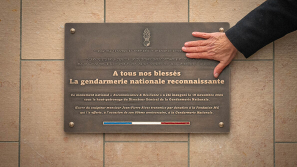Une plaque en acier apos&eacute;e sur un socle en pierre de couleur claire porte l'inscription "A tous nos bless&eacute;s, la gendarmerie nationale reconnaissante", ainsi q'une inscription en &eacute;criture braille, ainsi qu'un lisere&eacute; bleu blanc rouge