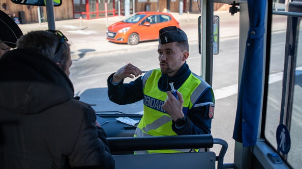 Un gendarme en train d'échanger avec un conducteur de bus à l'intérieur du bus.