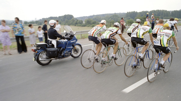 Photo d'archive montrant un militaire de la gendarmerie à moto derrière un peloton de cyclistes sur un route bordée