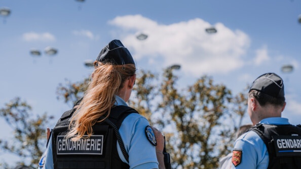 Gendarmes de dos regardant les parachutes decendre.