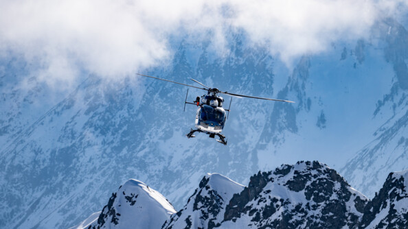 Vue d'un hélicoptère de la gendarmerie en plein vol au dessus des sommets enneigés des Pyrénnées.